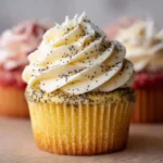 Lemon poppy seed cupcakes topped with a creamy frosting on a decorative plate.
